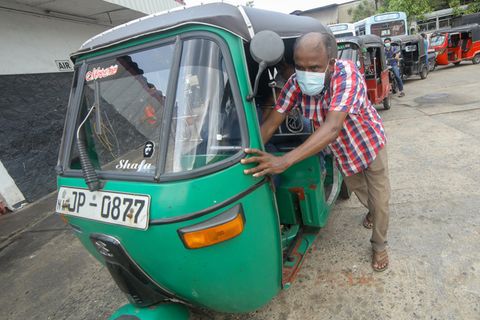 Ein Mann schiebt sein Tuk-Tuk in Sri Lanka zu einer Tankstelle.