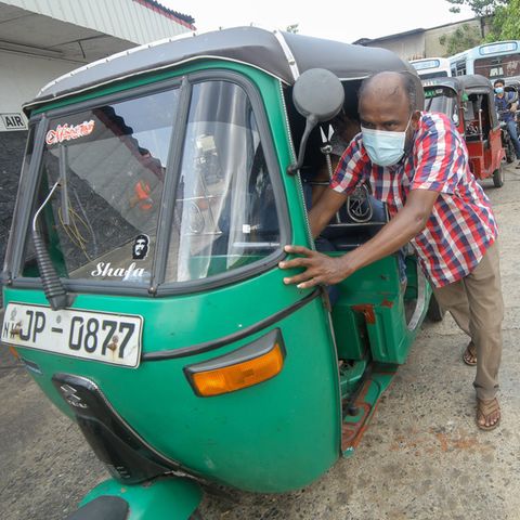 Ein Mann schiebt sein Tuk-Tuk in Sri Lanka zu einer Tankstelle.