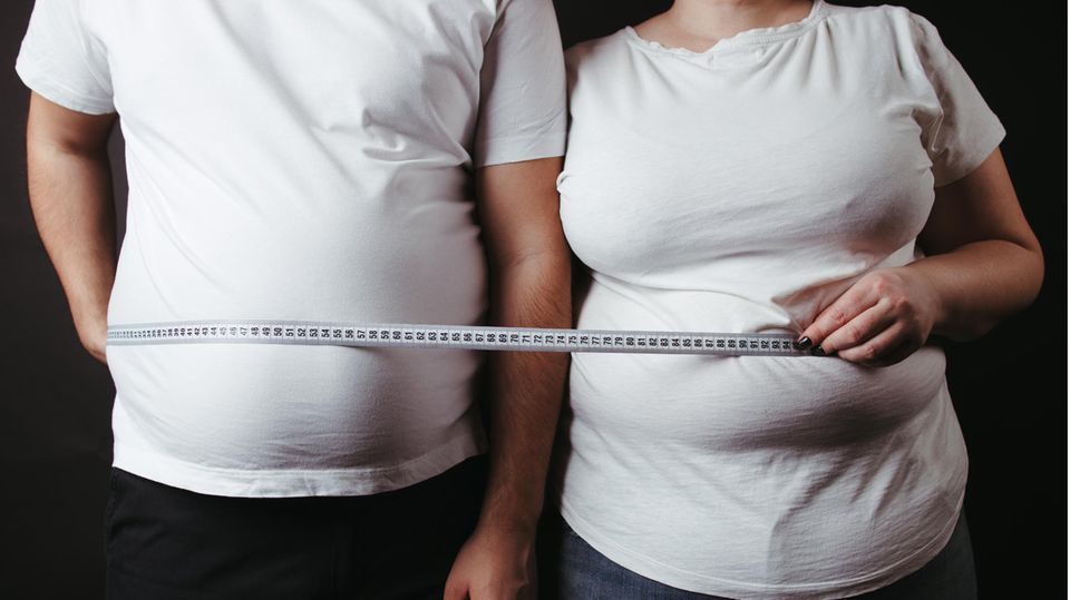 Zwei von Fettleibigkeit betroffene Menschen mit einem Maßband
