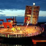 Die Bühne der Bregenzer Festspiele als überdimensionaler Café-Tisch. Riesige Stühle stehen darum. Bild von 2002