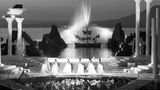 Säulen stehen am Rand der Bühne der Bregenzer Festspiele. Im Hintergrund speit eine Fontäne Wasser. Aufnahme von 1963