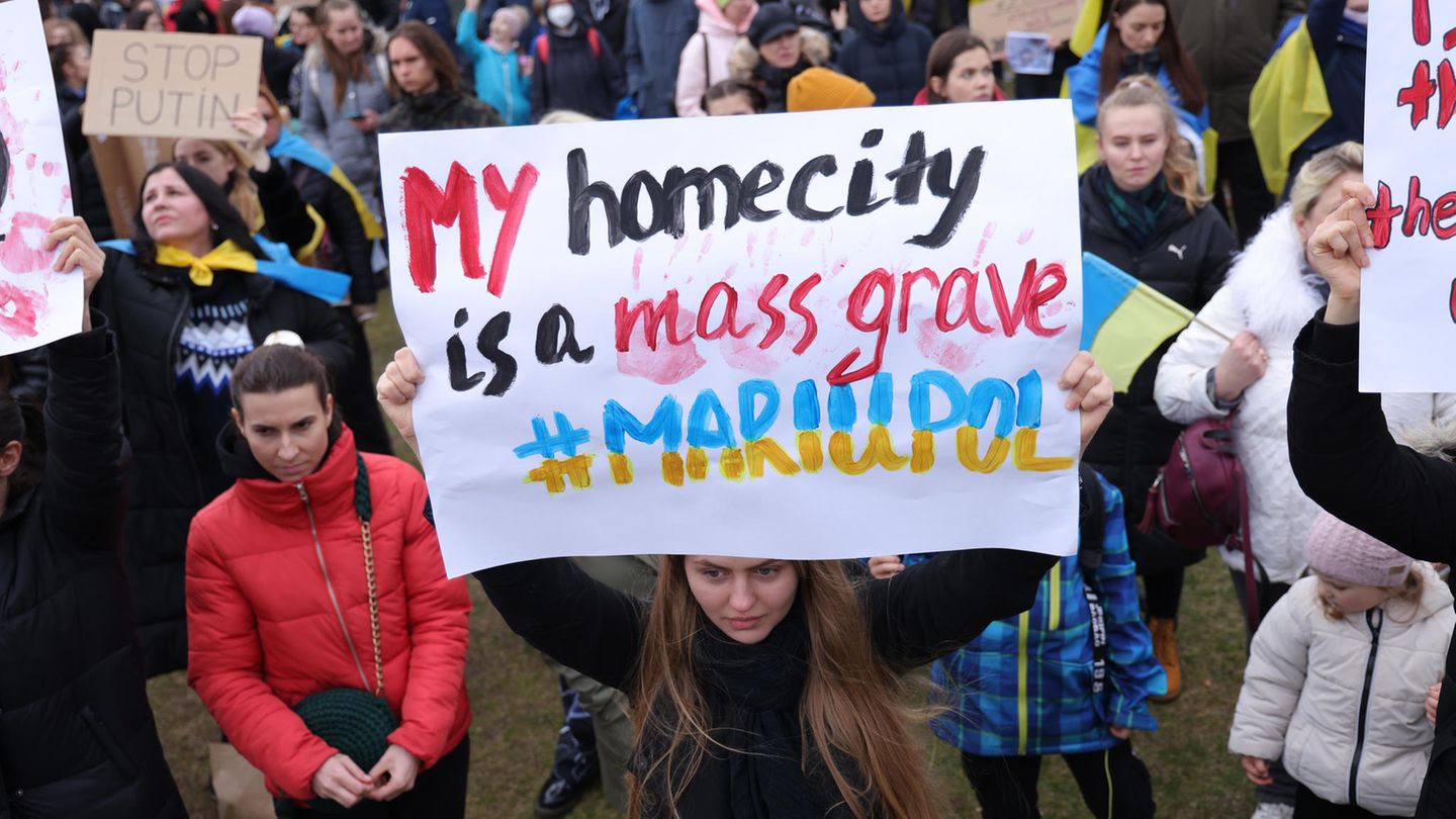 Demonstranten aus Mariupol mit Schild "My Hometown is a mass grave #Mariupol"