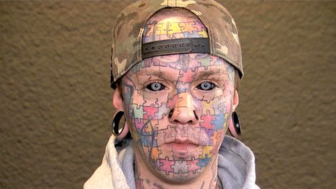 Tattoo-Kunstwerk: Mann hat Puzzle im Gesicht und schwarze Augäpfel
