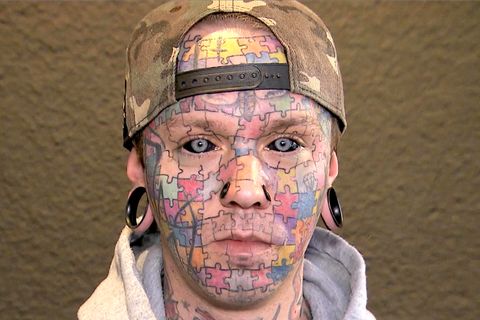 Tattoo-Kunstwerk: Mann hat Puzzle im Gesicht und schwarze Augäpfel