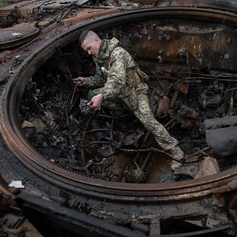 Ein ulkrainsicher Soldat  steht im Wrack eines ausgebrannten Panzers, dem das Geschütz fehlt