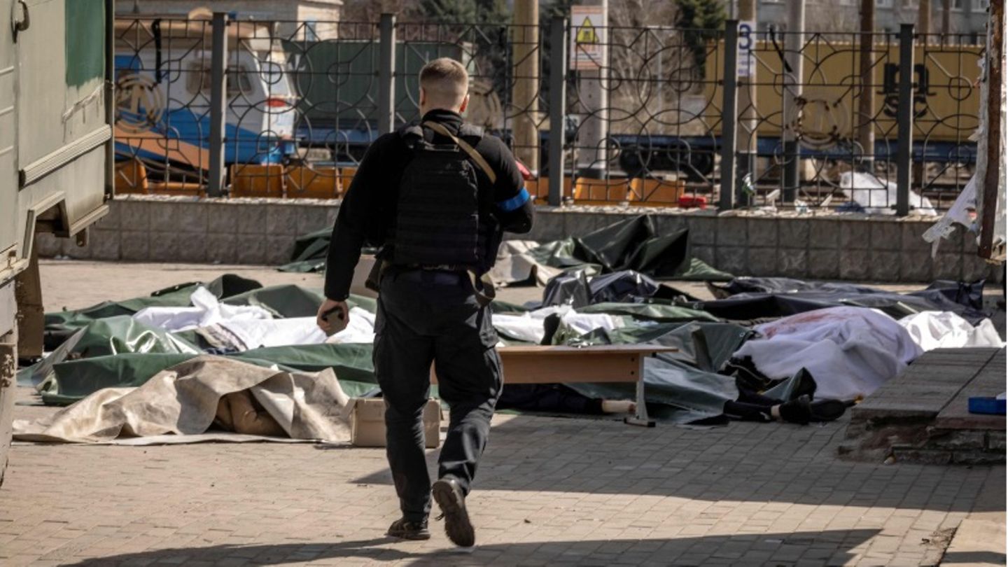 Kramatorsk, Ukraine: A police officer walks towards several bodies covered with plastic sheets lying on the ground. Kramatorsk, Ukraine: A police officer walks towards several bodies covered with plastic sheets lying on the ground.