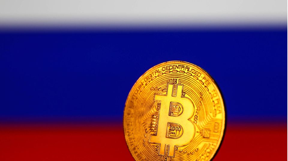 Eine fiktive Bitcoin-Münze steht vor einer Russland-Flagge
