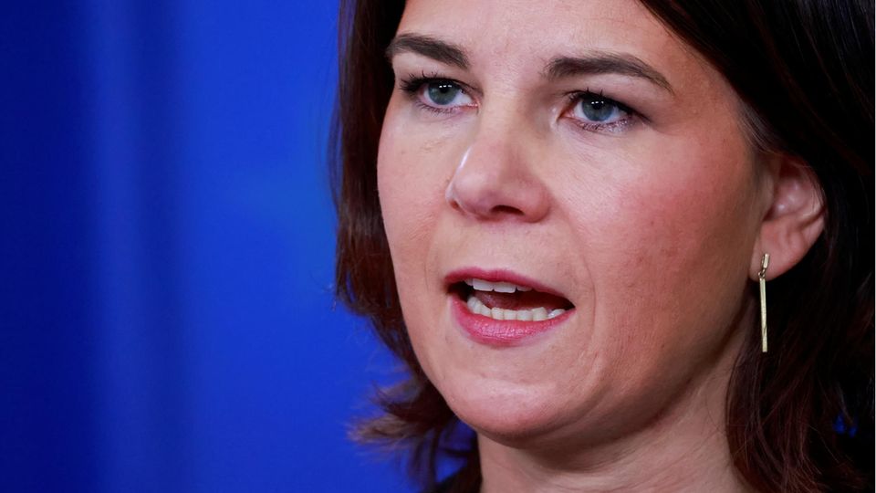 Eine weiße Frau mit schulterlangem braunem Haar hat beim Sprechen den Mund offen