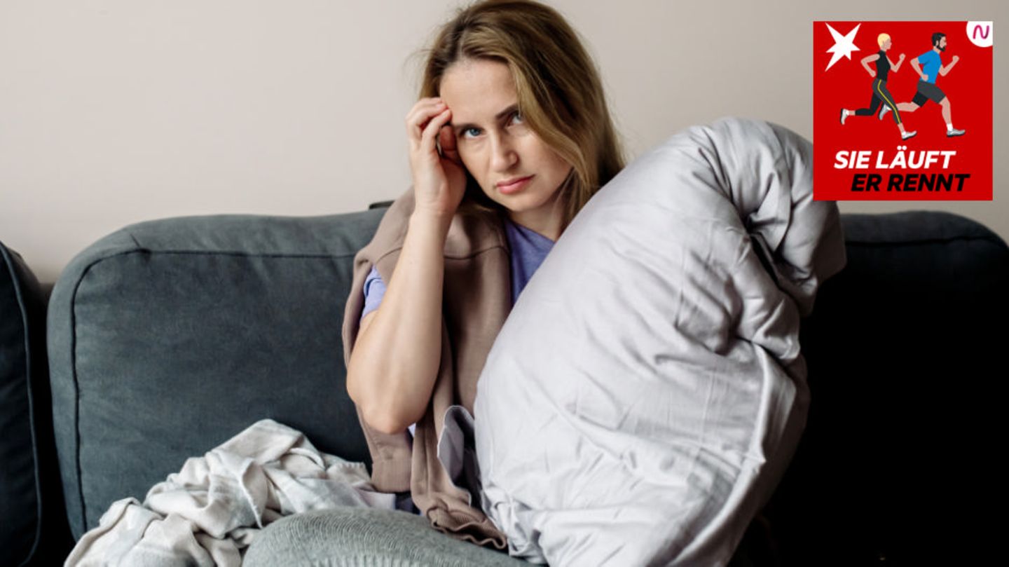 Eine kranke Frau sitzt mit Kissen auf dem Sofa