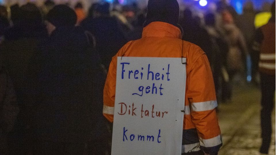 Ein Demonstrant bei einer Querdenken-Demo mit einem Schild "Freiheit geht, Diktatur kommt"