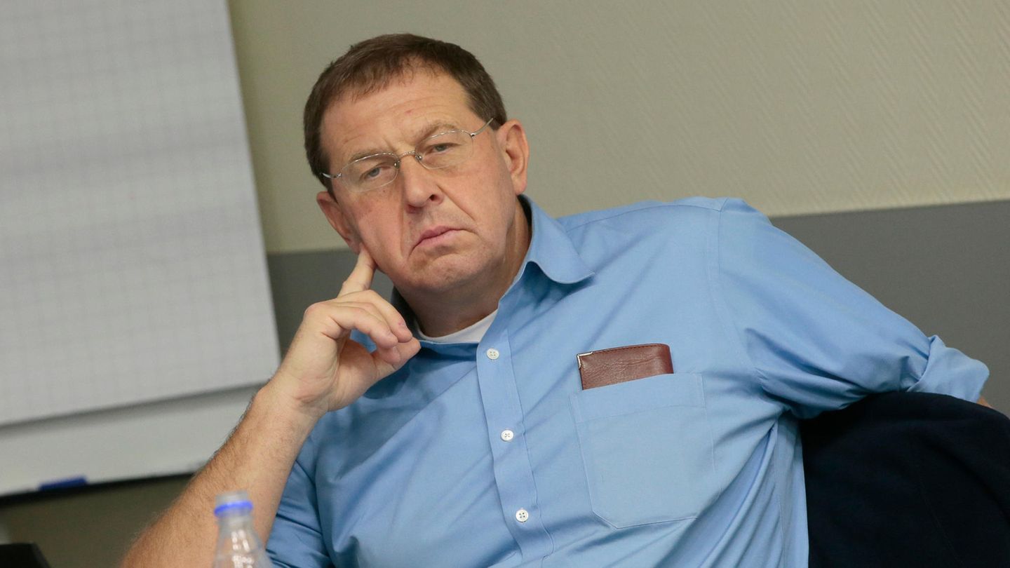 Andrej Illarionov sitzt auf einem Stuhl und hält seinen rechten Zeigefinger an seine Wange