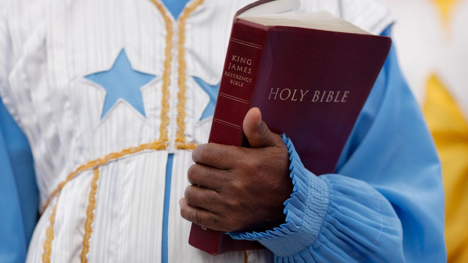 Ein Geistlicher hält die "Heilige Bibel" in seinem Arm
