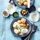 Vegane Königsberger Klopse      Zutaten für 4 Portionen:  Zutaten für Klopse:  1 Zwiebel, 40 g Walnüsse, 40 g Pekannüsse, 170 g Haferflocken blütenzart, 2 EL Speiseöl, 1200 ml Brühe oder Gemüsefond, 60 g glatte Petersilie, 1 EL mittelscharfer Senf, Salz, Pfeffer, Paprika edelsüß, 1 Lorbeerblatt  Zutaten für die Sauce:  5 EL Speiseöl, 4 EL Mehl, 200 ml Kochbrühe der Klopse, 200 ml Pflanzliche Kochsahne, 1 EL Zitronensaft, 1 Glas Kapern und der Saft davon, Salz  Pfeffer, Muskatnuss      Zubereitung:  Zwiebel schälen und fein würfeln. Nüsse fein im Mixer zerkleinern und mit Haferflocken vermengen. Zwiebeln in einer Pfanne mit Butterschmalz glasig dünsten. Nuss-Haferflocken-Gemisch hinzufügen und kurz anrösten. 200 ml Gemüsebrühe hinzugeben, umrühren und vom Herd nehmen. Petersilie fein hacken und die Hälfte zur Klopsmasse hinzugeben. Diese mit den Gewürzen und Senf abschmecken und mithilfe einer Gabel zu einem Klopsteig vermengen.  Restliche Gemüsebrühe in einem großen Topf erwärmen – sie darf nicht kochen. Derweil aus dem Klopsteig gleichmäßig viele Klopse formen und anschließend vorsichtig in die Brühe geben. Darin 10 Minuten ziehen lassen und mit einer Schaumkelle wieder rausholen. Klopse warm stellen.  Für die Sauce Butterschmalz in einem Topf erhitzen. Wenn das Mehl hinzugefügt wird, muss schnell und kräftig gerührt werden. Anschließend sofort die Kochbrühe der Klopse hinzufügen und weiterrühren. Pflanzliche Kochsahne, Kapern, Saft der Kapern, Zitronensaft und restliche Petersilie beimengen. Mit den Gewürzen abschmecken. Die Klopse zusammen mit der Sauce servieren. Dazu passen Pellkartoffeln oder Reis.