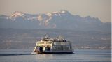 Eine Fähre überquert vor Bergkulisse den Bodensee
