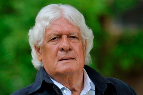 Ein älterer weißer Mann mit weißem, gelockten Mittelscheitel schaut ernst