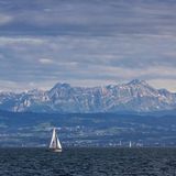 Zwei Segelboote fahren vor Bergpanorama auf dem Bodensee