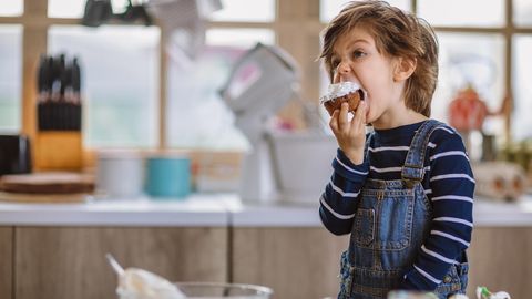 Ein kleiner Junge beißt in einen Schoko-Muffin
