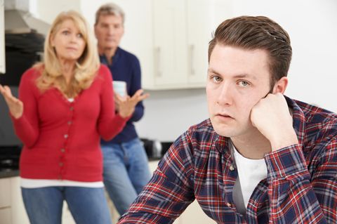 Sohn sitzt in der Küche und ist von seinen Eltern genervt