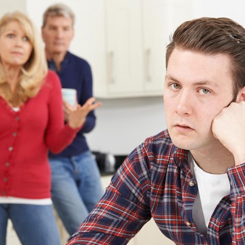 Sohn sitzt in der Küche und ist von seinen Eltern genervt