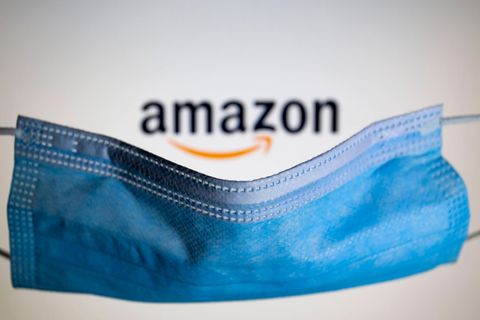 Symbolfoto: Ein Mundschutz liegt über dem Amazon-Logo