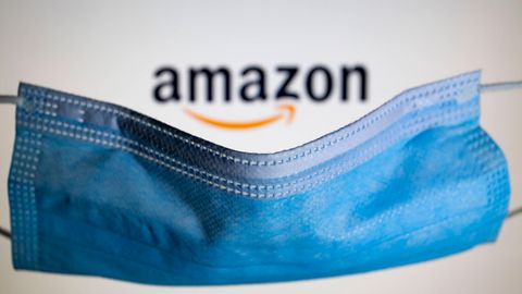 Symbolfoto: Ein Mundschutz liegt über dem Amazon-Logo