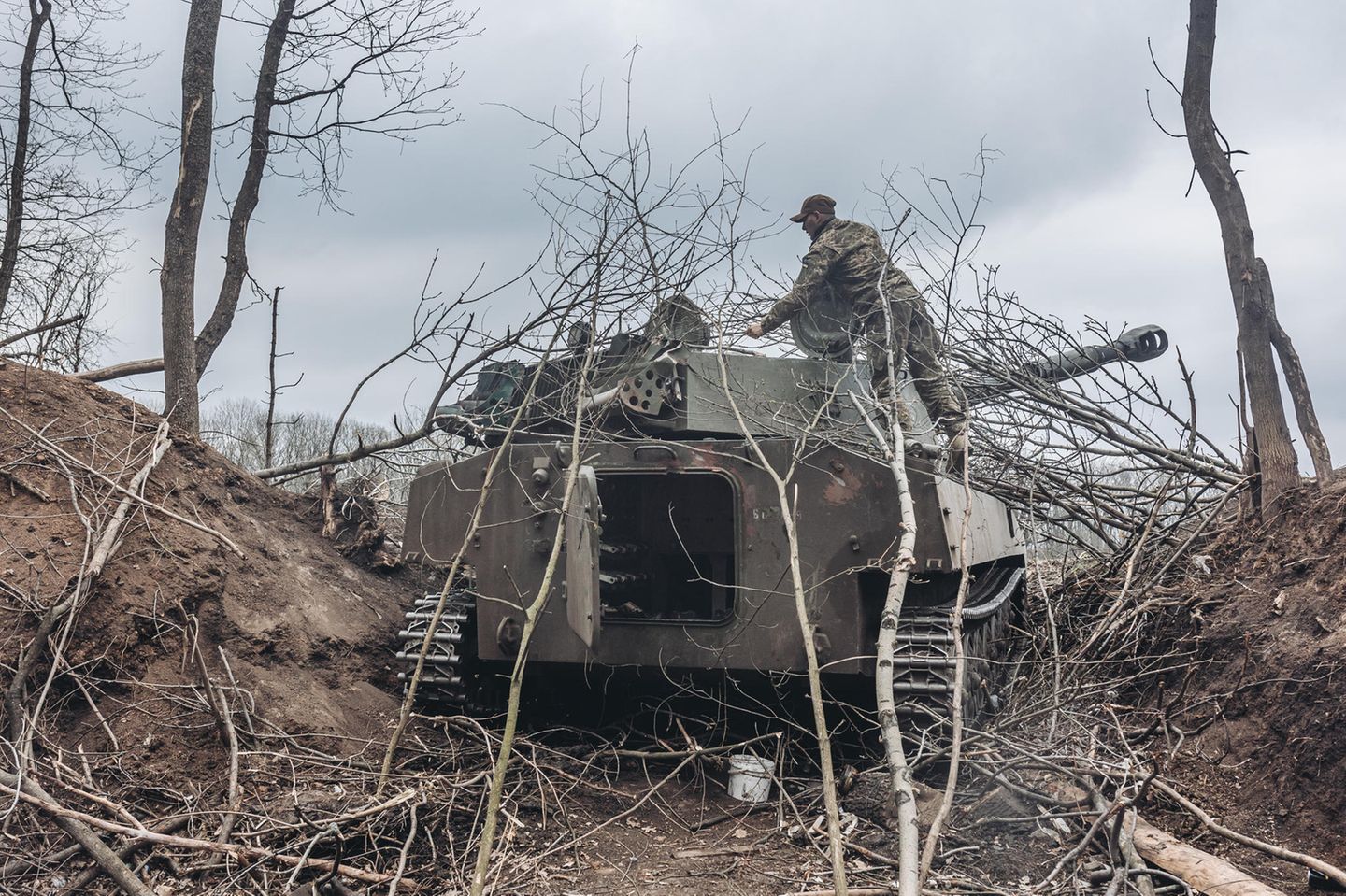 Warten auf den Feind. Ein Soldat der Ukraine tarnt einen Panzer notdürftig mit Zweigen.