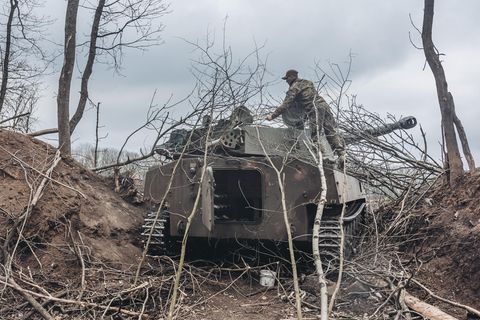 Warten auf den Feind. Ein Soldat der Ukraine tarnt einen Panzer notdürftig mit Zweigen.