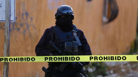 Ein schwer bewaffneter Soldat mit Maske steht in Mexiko hinter einem Absperrband