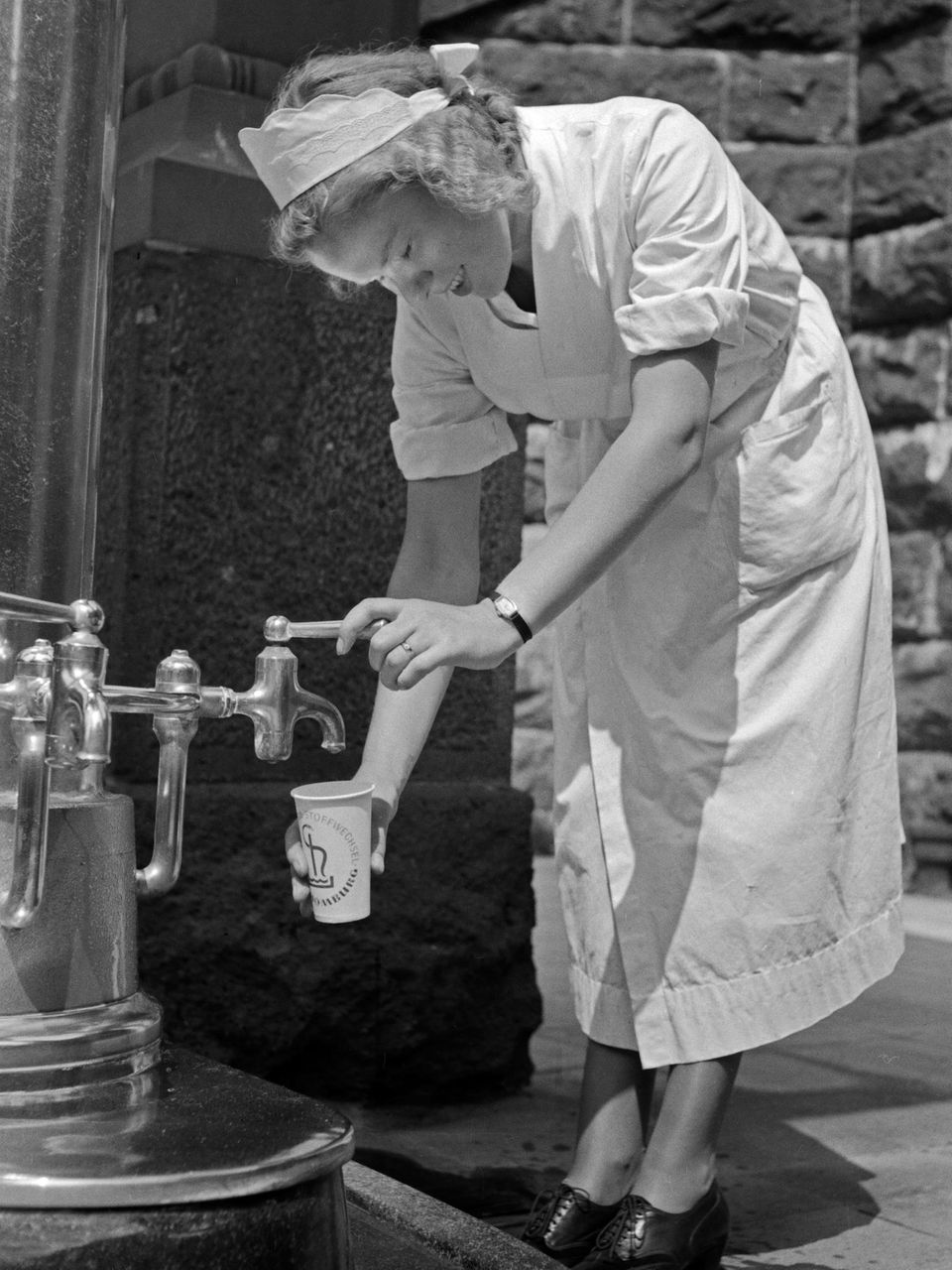 Eine Krankenschwester füllt einen Becher mit Wasser Eine Krankenschwester füllt einen Becher mit Wasser