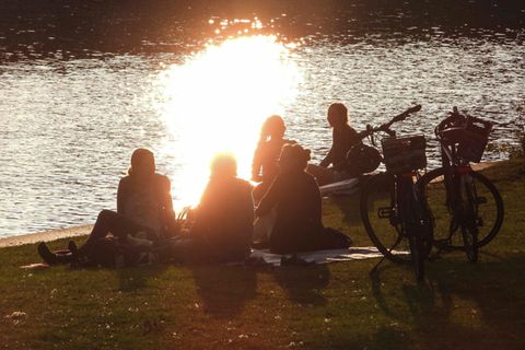 Ein paar Menschen sitzen in Hamburg am Wasser. Die Sonne scheint. Die Stimmung ist gut. Was macht Wetterfühligkeit mit uns?