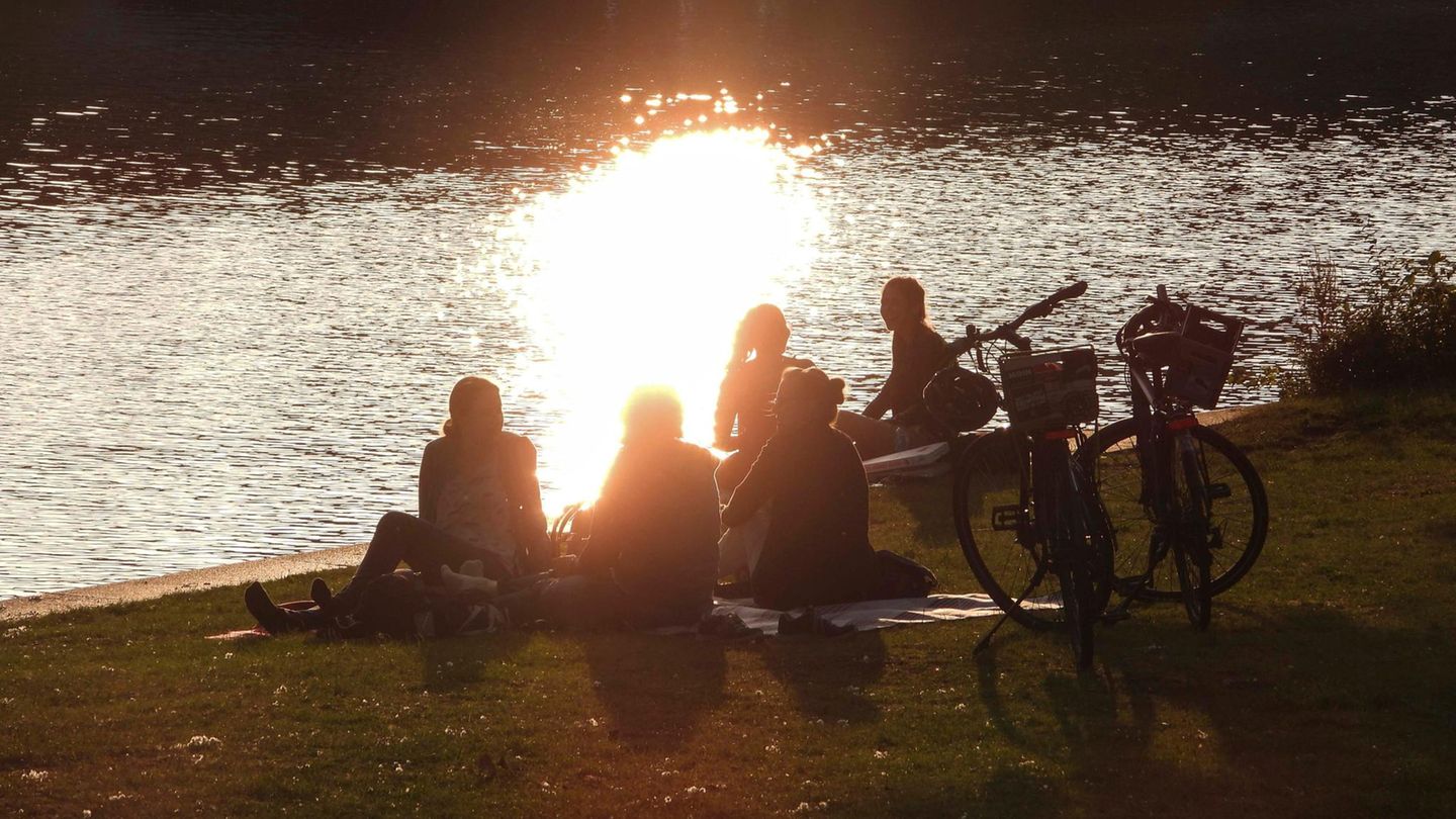 Ein paar Menschen sitzen in Hamburg am Wasser. Die Sonne scheint. Die Stimmung ist gut. Was macht Wetterfühligkeit mit uns?