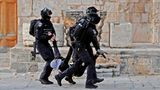 Drei Polizisten in schwarzen Uniformen und Helmen tragen einen mit Palästinensertuch vermummten jungen Mann weg