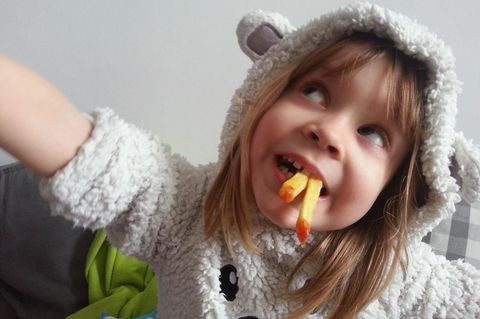 Ein kleines Mädchen isst Pommes