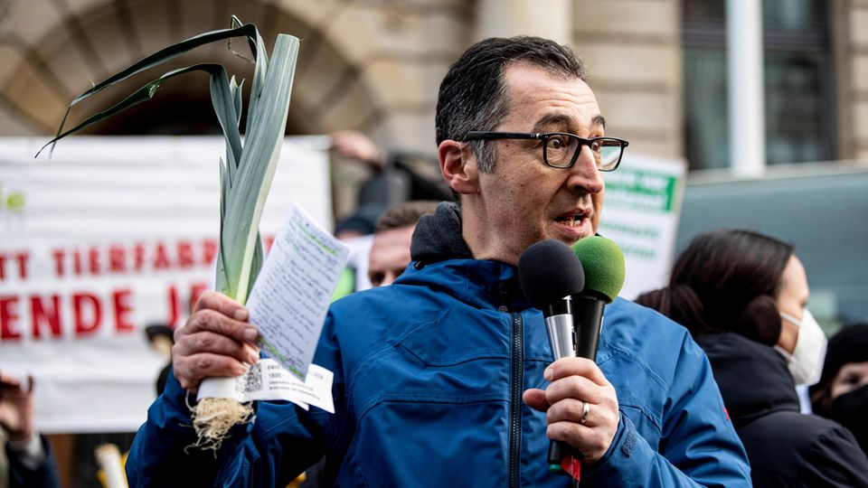 Cem Özdemir hält einen Lauch in der Hand und spricht bei einer Demonstration