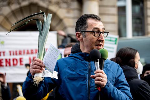 Cem Özdemir hält einen Lauch in der Hand und spricht bei einer Demonstration