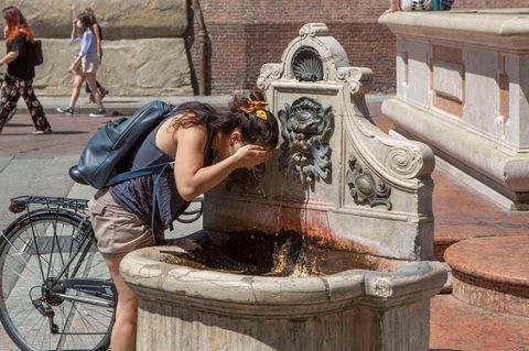 Eine Frau erfrischt an einem öffentlichen Brunnen in Bologna