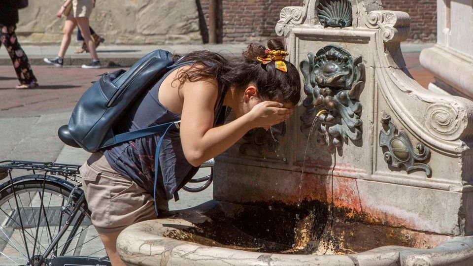 Eine Frau erfrischt an einem öffentlichen Brunnen in Bologna