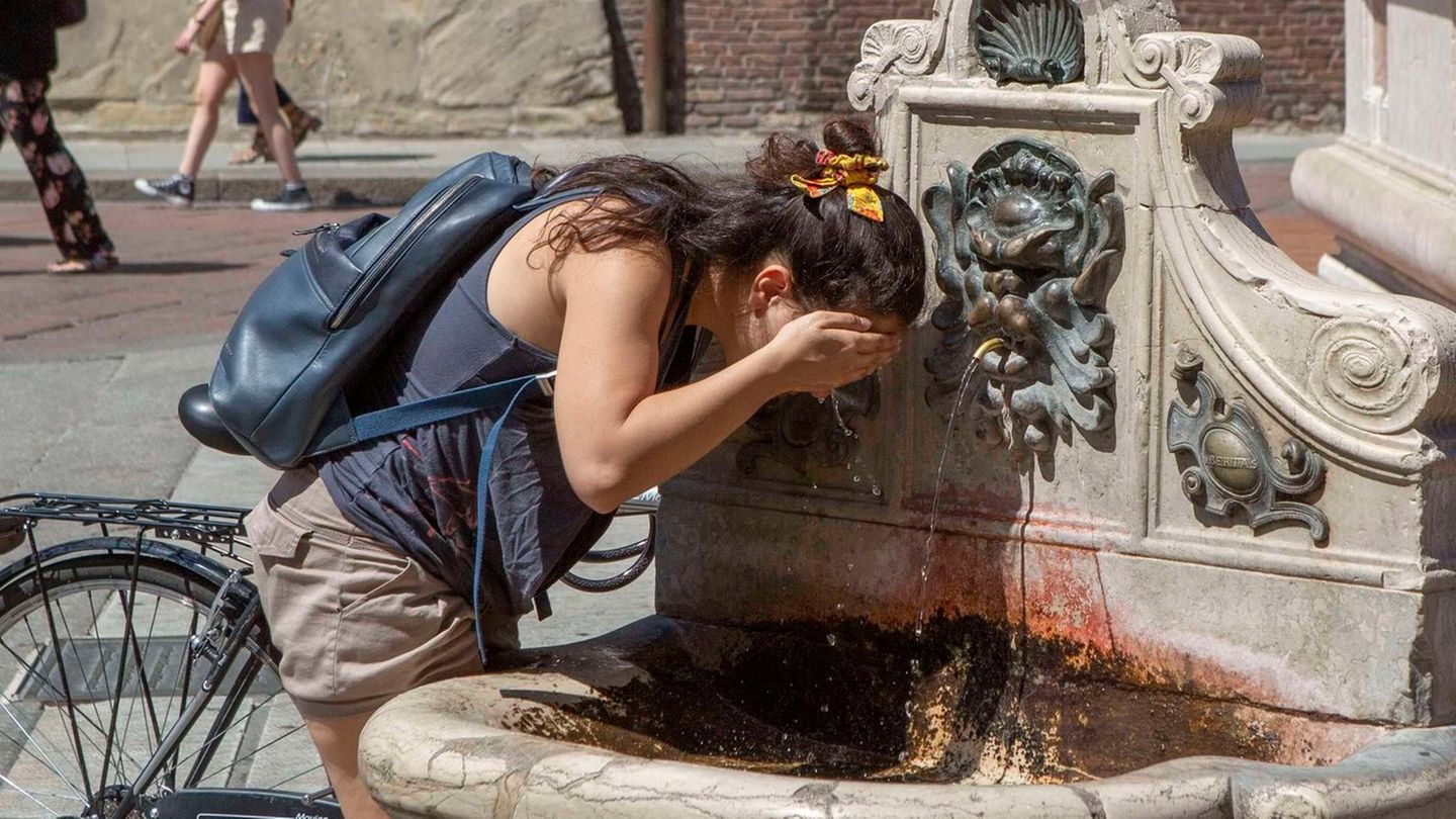 Eine Frau erfrischt an einem öffentlichen Brunnen in Bologna