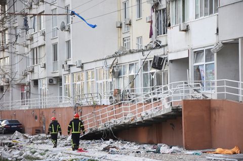 Ukraine, Odessa: Feuerwehrleute gehen auf einem Weg vor einem Wohnhaus