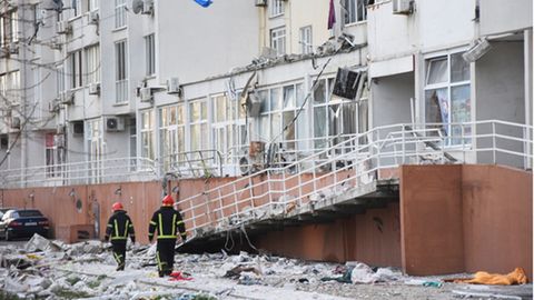 Ukraine, Odessa: Feuerwehrleute gehen auf einem Weg vor einem Wohnhaus
