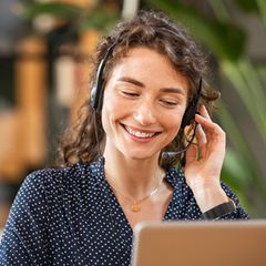 Eine lachende Frau telefoniert, mit einem Headset