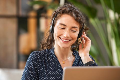 Eine lachende Frau telefoniert, mit einem Headset