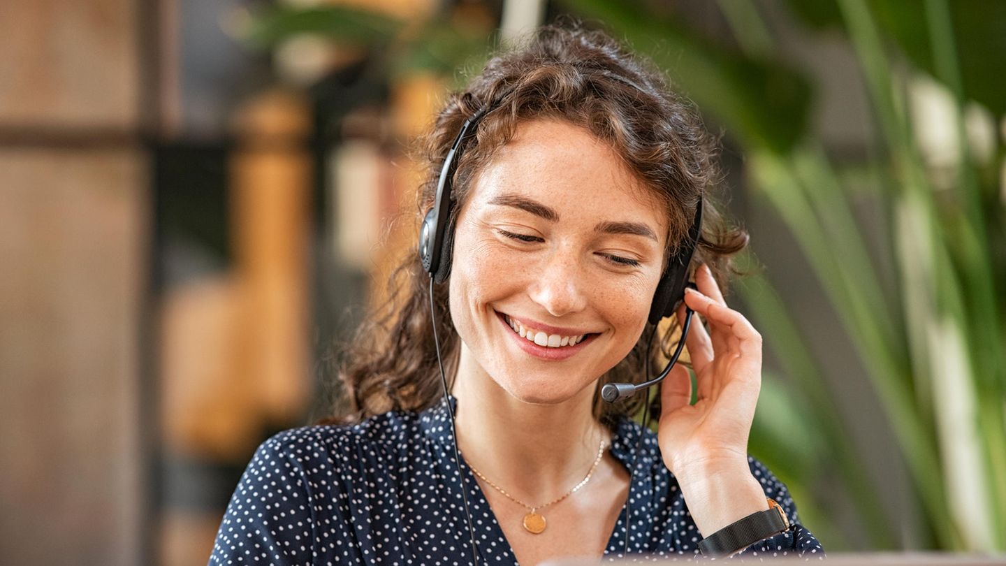 Eine lachende Frau telefoniert, mit einem Headset