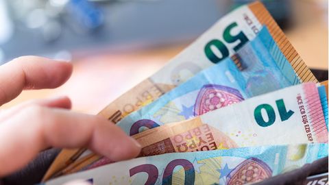 Eine Frau hält eine Geldbörse mit Banknoten in der Hand
