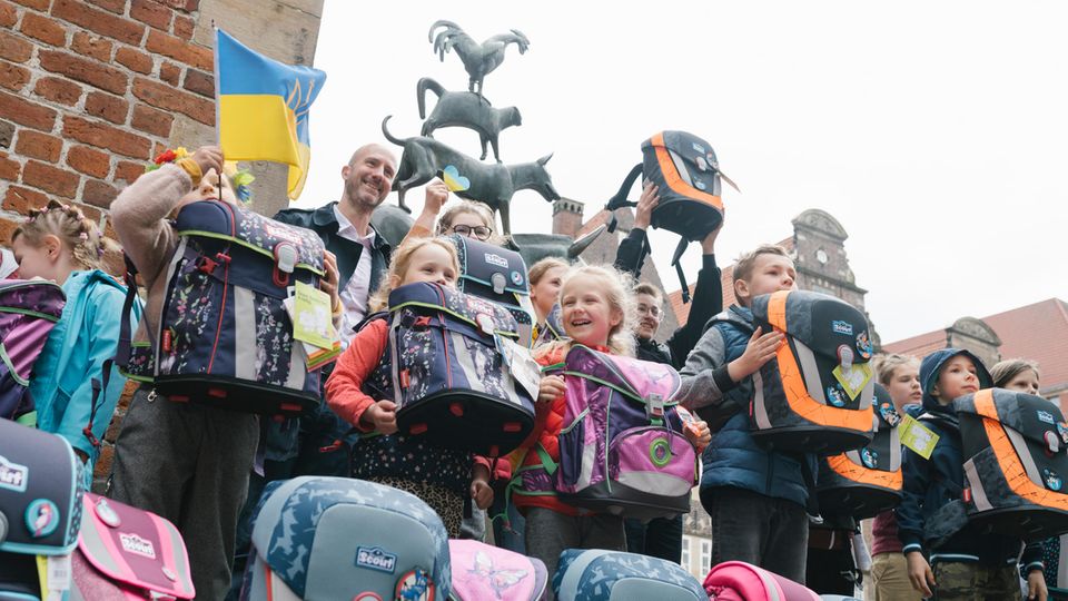 Ein kleines Stück Alltag: Auf dem Marktplatz von Bremen erhalten aus der Ukraine geflüchtete Jungen und Mädchen die mit Spendengeldern angeschafften Schulranzen der Stiftung stern und des Deutschen Kinderhilfswerks