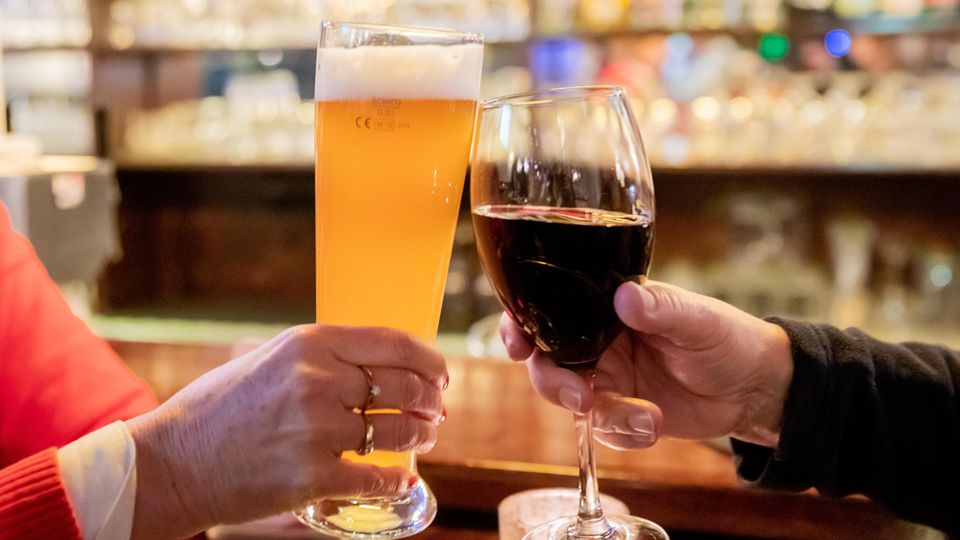 Zwei Gäste stoßen in einer Gaststätte mit Wein und Bier an. Laut Sucht-Jahresbericht ist Deutschland "Hochkonsumland".
