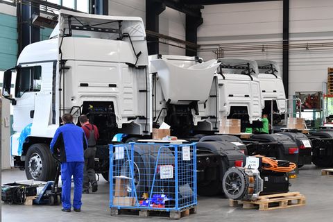 Mitarbeiter rüsten in einer Produktionshalle einen Diesel-LKW zum Elektrofahrzeug um