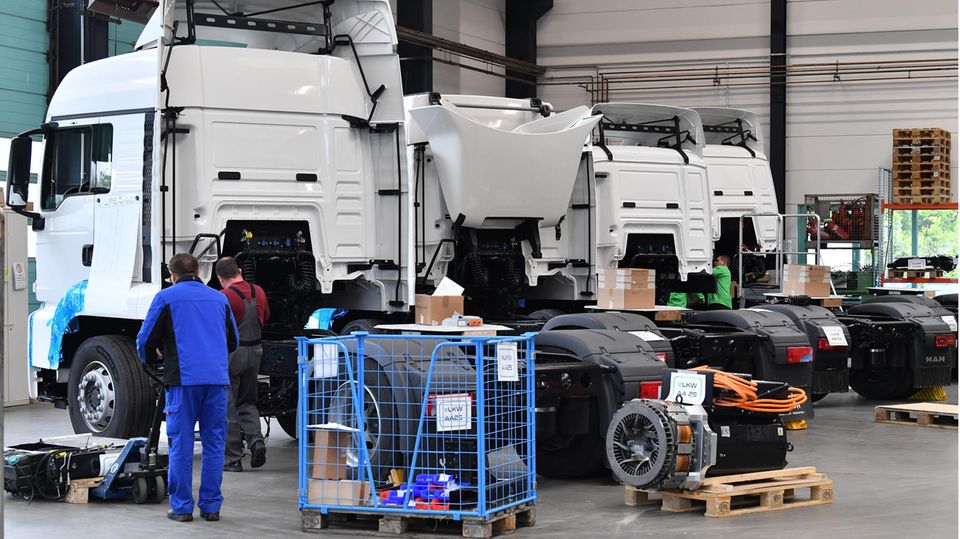 Mitarbeiter rüsten in einer Produktionshalle einen Diesel-LKW zum Elektrofahrzeug um