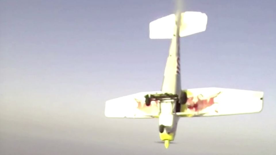 Ein weiß, gelb und rot lackiertes Sportflugzeug mit Propeller stürzt auf den Boden zu