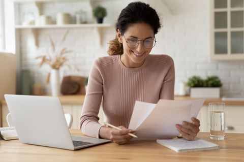 Eine Frau sitzt mit einer Rechnung vor ihrem Laptop